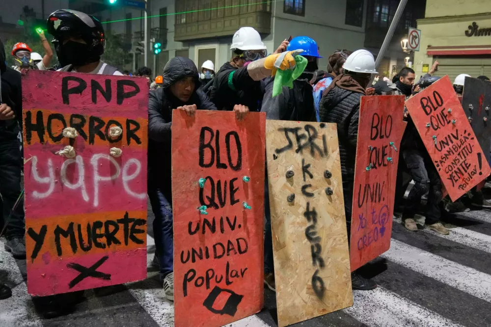 Demonstrators take refuge behind shields from police during a protest against new President Jose Jeri in Lima, Peru, Wednesday, Oct. 15, 2025. (AP Photo/Martin Mejia)