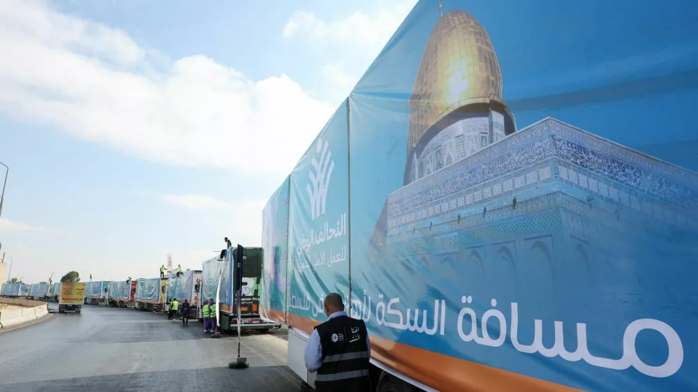 A man walks next to trucks loaded with humanitarian aid from Egypt's National Alliance For Civil Development Work (NACDW) as they are on their way to the Rafah border crossing to enter Gaza, after a ceasefire between Israel and Hamas in Gaza went into effect, on the Cairo-Ismailia desert road, in Egypt, October 16, 2025. REUTERS/Amr Abdallah Dalsh