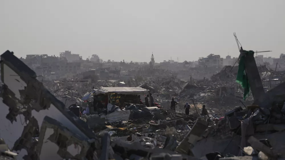 Palestinians walk among destroyed buildings in Gaza City, Thursday, Oct. 16, 2025. (AP Photo/Jehad Alshrafi)