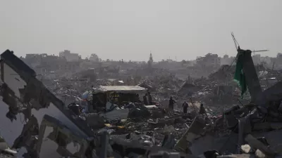 Palestinians walk among destroyed buildings in Gaza City, Thursday, Oct. 16, 2025. (AP Photo/Jehad Alshrafi)