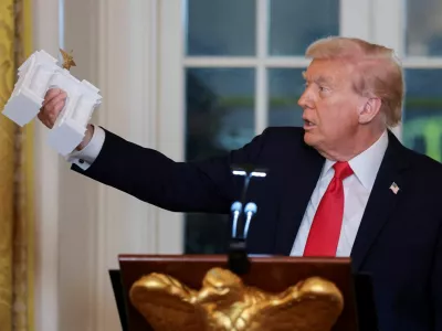 U.S. President Donald Trump holds a model of an arch monument during a ballroom dinner in the East Room at the White House in Washington, D.C., U.S., October 15, 2025. REUTERS/Jonathan Ernst