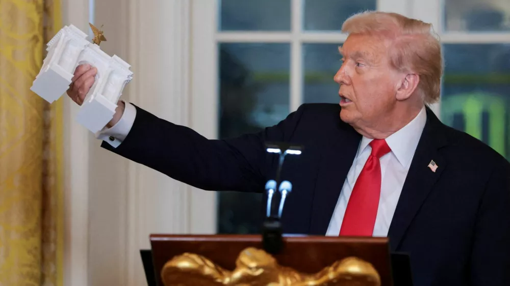 U.S. President Donald Trump holds a model of an arch monument during a ballroom dinner in the East Room at the White House in Washington, D.C., U.S., October 15, 2025. REUTERS/Jonathan Ernst