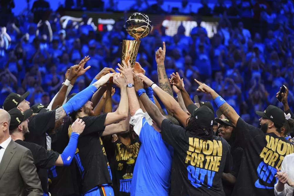 Oklahoma City Thunder players hold up the Larry O'Brien Championship Trophy after they won the NBA basketball championship with a Game 7 victory against the Indiana Pacers Sunday, June 22, 2025, in Oklahoma City. (AP Photo/Julio Cortez)