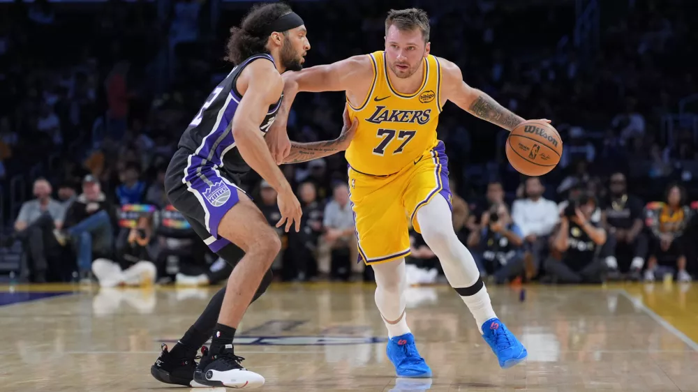 Los Angeles Lakers guard Luka Doncic (77) works around Sacramento Kings guard Devin Carter (22) during the first half of a preseason NBA basketball game Friday, Oct. 17, 2025, in Los Angeles. (AP Photo/Jae C. Hong)