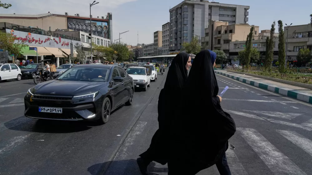 Two women cross the Enqelab-e-Eslami (Islamic Revolution) square, in Tehran, Iran, Saturday, Sept. 27, 2025. (AP Photo/Vahid Salemi)