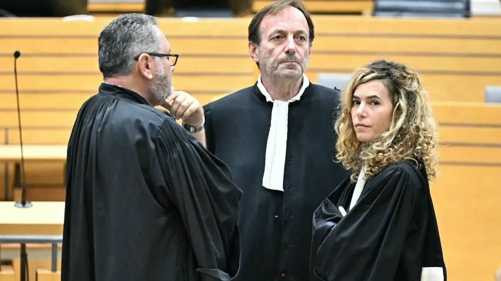 17 October 2025, France, Albi: Defendant's lawyers Alexandre Martin (C) and Emmanuelle Franck (R) wait for the opening of their client's trial for the murder of his wife in the courtroom of the Tarn Assize Courthouse. In a trial without a body, witnesses, or confession, a court in France has sentenced a man to 30 years in prison for the murder of his wife. Photo: Lionel Bonaventure/AFP/dpa