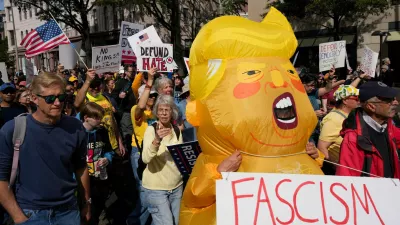 A person wearing an inflatable costume depicting U.S. President Donald Trump and demonstrators take part in a "No Kings" protest against U.S. President Donald Trump's policies, in Washington, D.C., U.S., October 18, 2025. REUTERS/Leah Millis