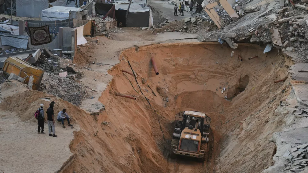 Palestinians watch members of the Hamas militant group searching for bodies of the hostages in Khan Younis, southern Gaza Strip, Saturday, Oct. 18, 2025. (AP Photo/Jehad Alshrafi)