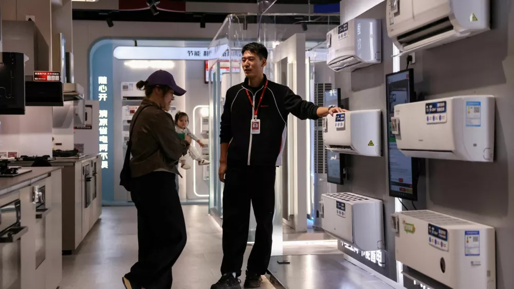 A staff member attends to a customer at an air conditioner booth at a home appliance mall in Beijing, China October 19, 2025. REUTERS/Tingshu Wang
