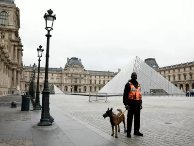 A security employee with a dog stands near the glass Pyramid of the Louvre Museum as the museum remains closed the day after a spectacular jewel heist by thieves who broke into the landmark by using a crane and smashing an upstairs window, stealing priceless jewelry from an area that houses the French crown jewels before escaping on motorbikes, in Paris, France, October 20, 2025. REUTERS/Benoit Tessier