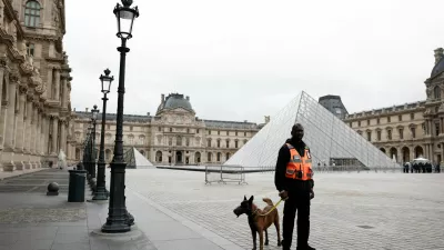 A security employee with a dog stands near the glass Pyramid of the Louvre Museum as the museum remains closed the day after a spectacular jewel heist by thieves who broke into the landmark by using a crane and smashing an upstairs window, stealing priceless jewelry from an area that houses the French crown jewels before escaping on motorbikes, in Paris, France, October 20, 2025. REUTERS/Benoit Tessier
