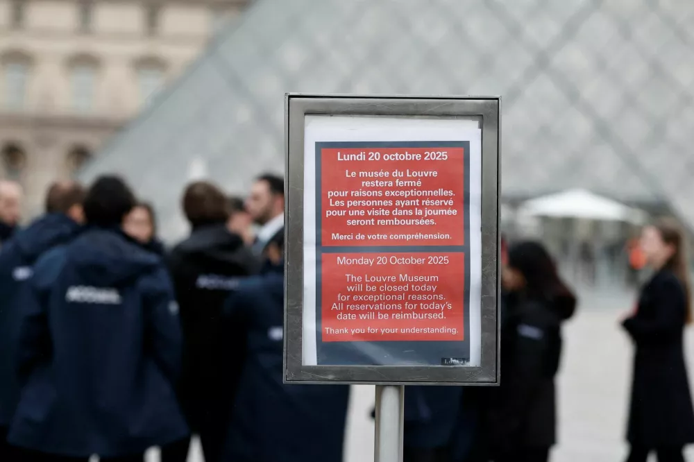 A placard which reads "The Louvre Museum will be closed today for exceptional reasons" is seen near the glass Pyramid of the Louvre Museum as the museum remains closed the day after a spectacular jewel heist by thieves who broke into the landmark by using a crane and smashing an upstairs window, stealing priceless jewelry from an area that houses the French crown jewels before escaping on motorbikes, in Paris, France, October 20, 2025. REUTERS/Benoit Tessier