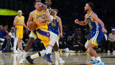 Los Angeles Lakers' Luka Dončić, left, is defended by Golden State Warriors guard Jonathan Kuminga during the first half of an NBA basketball game Tuesday, Oct. 21, 2025, in Los Angeles. (AP Photo/Ethan Swope)