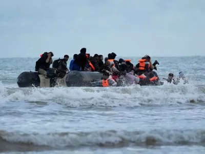 22 October 2025, France, Gravelines: People thought to be migrants wade through the sea to board a small boat in Gravelines. Photo: Gareth Fuller/PA Wire/dpa