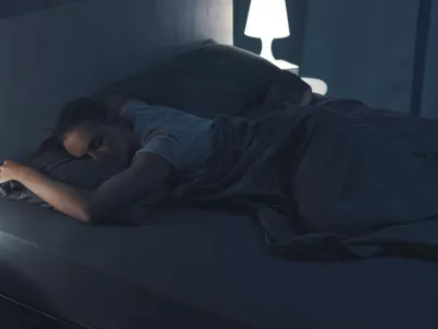 Woman sleeping in her bed at night, she is lying on her stomach / Foto: Cyano66