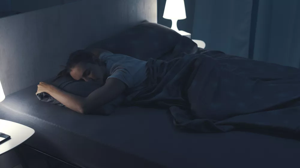 Woman sleeping in her bed at night, she is lying on her stomach / Foto: Cyano66