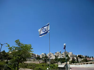 FILE PHOTO: The Israeli national flag flutters as apartments are seen in the background in the Israeli settlement of Maale Adumim in the Israeli-occupied West Bank August 16, 2020. Picture taken August 16, 2020. REUTERS/Ronen Zvulun/File Photo
