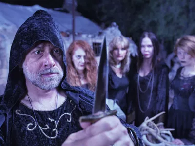 Pagan priest with ritual dagger and coven at altar