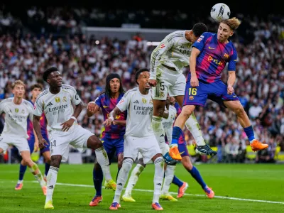 Barcelona's Fermin Lopez, top right, goes for a header with Real Madrid's Jude Bellingham during the Spanish La Liga soccer match between Real Madrid and Barcelona, in Madrid, Sunday, Oct. 26, 2025. (AP Photo/Manu Fernandez)