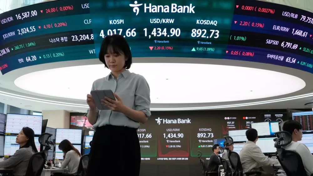 Currency traders works near a screen showing the Korea Composite Stock Price Index (KOSPI), top center left, and the foreign exchange rate between U.S. dollar and South Korean won, top center, at the foreign exchange dealing room of the Hana Bank headquarters in Seoul, South Korea, Monday, Oct. 27, 2025. (AP Photo/Ahn Young-joon)