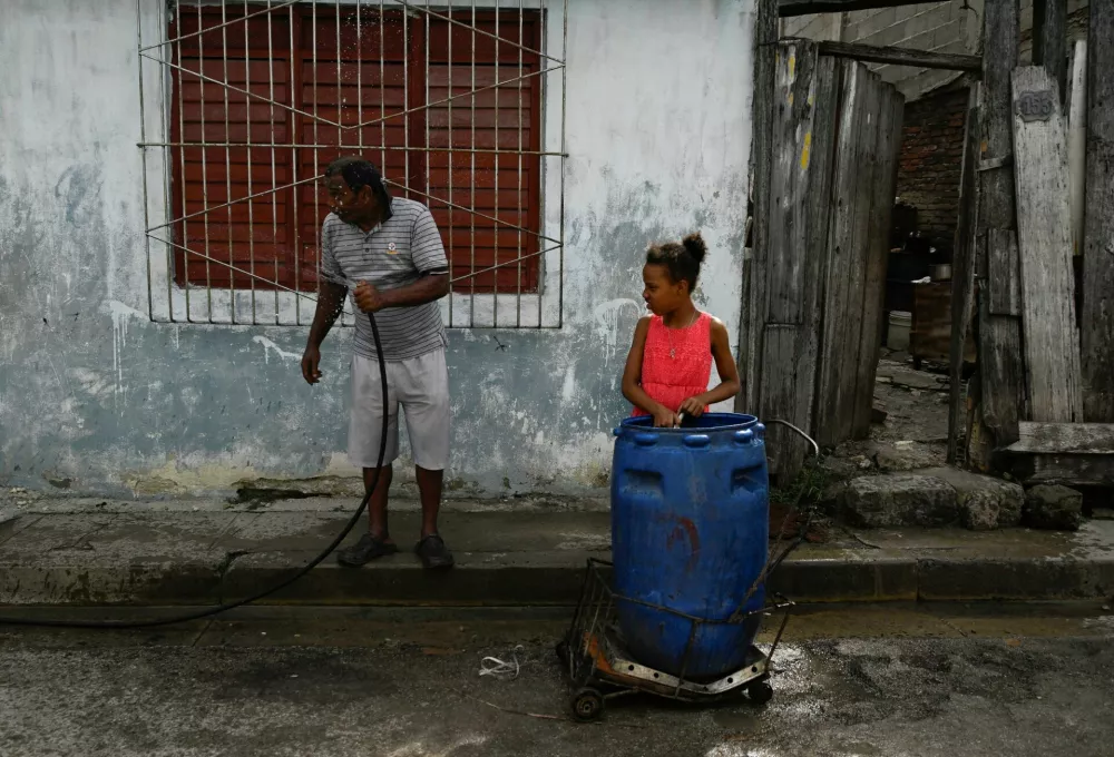 People gather drinking water in a plastic barrel ahead of the arrival of Hurricane Melissa, in Havana, Cuba, October 27, 2025. REUTERS/Norlys Perez