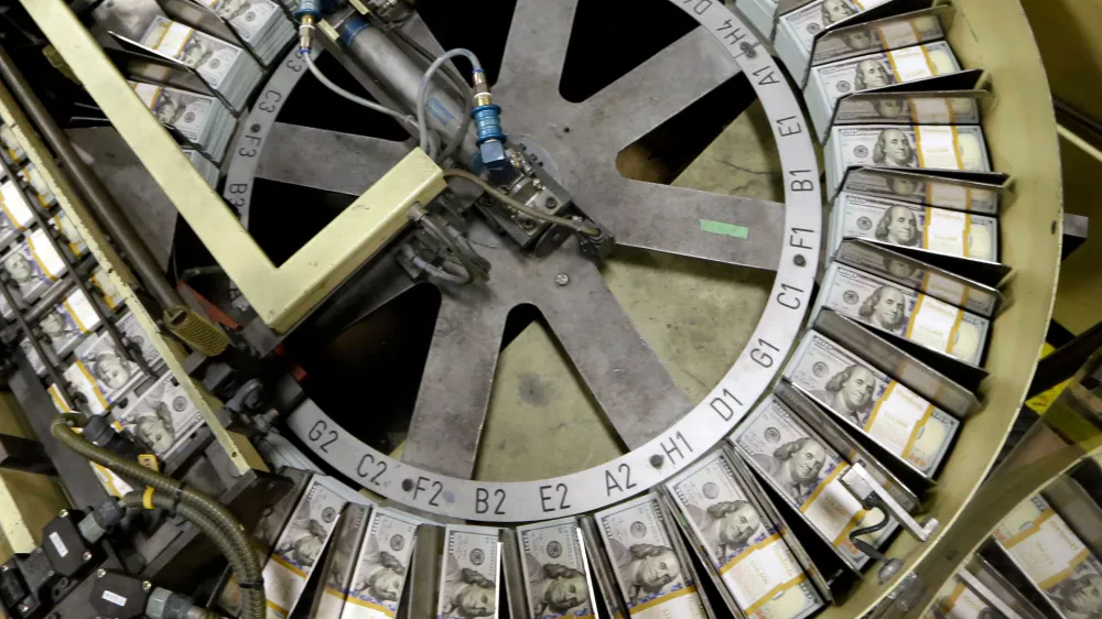 FILE - In this Sept. 24, 2013 file photo, freshly cut stacks of $100 bills make their way down the line at the Bureau of Engraving and Printing Western Currency Facility in Fort Worth, Texas. (AP Photo/LM Otero, File)