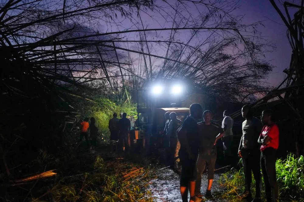 Workers clear downed trees and debris to make way for a convoy carrying aid to Black River, which was hit by Hurricane Melissa, as it moves through Holland Bamboo, Jamaica, Wednesday, Oct. 29, 2025. (AP Photo/Matias Delacroix)