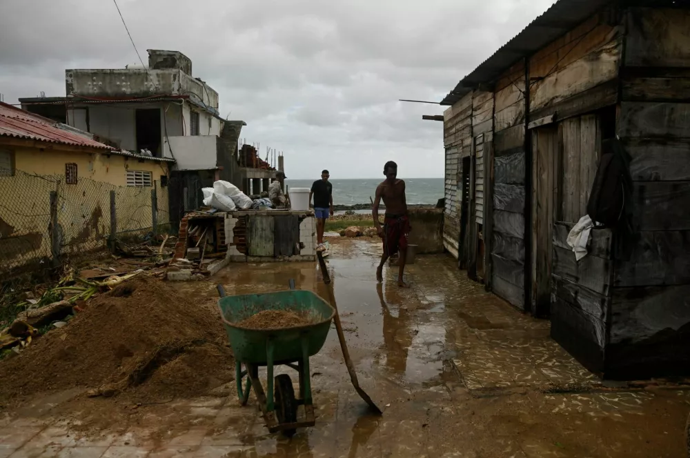 Residents stand next to their house in the aftermath of Hurricane Melissa, in Santiago, Cuba, October 29, 2025. REUTERS/Norlys Perez