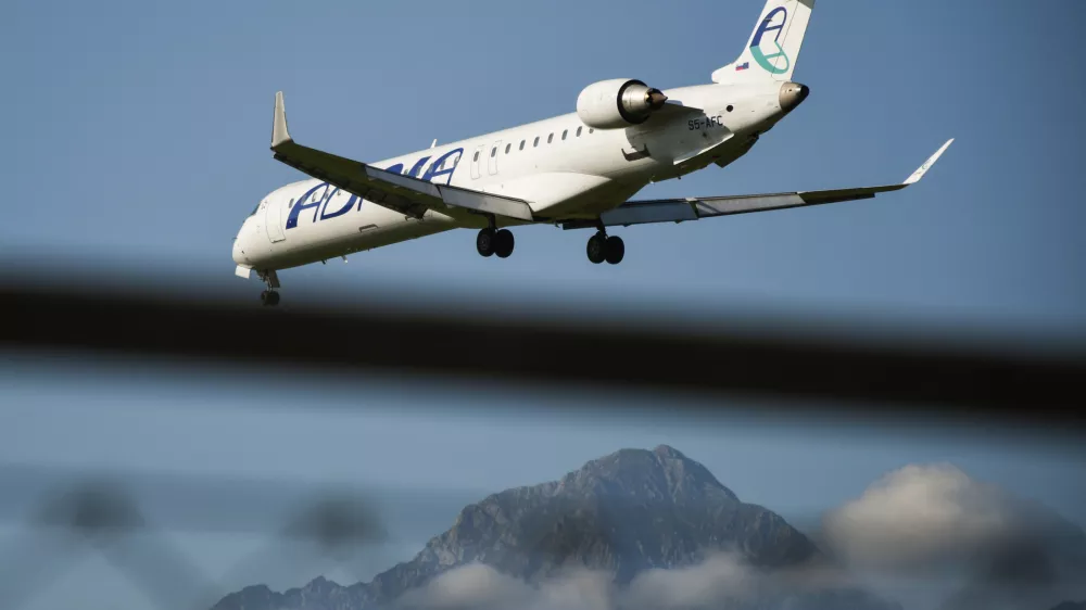 Ljubljana, Slovenia - September 15, 2019: Small Adria Airways passenger plane flying low on a clear sky sunny day with mountains in the background