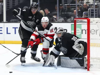Los Angeles Kings center Anze Kopitar, left, New Jersey Devils right wing Stefan Noesen (11), and Los Angeles Kings goaltender Darcy Kuemper (35) battle for the puck during the first period of an NHL hockey game, Saturday, Nov. 1, 2025, in Los Angeles. (AP Photo/Jessie Alcheh)