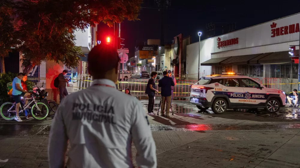 Policeman stands near a convenience store destroyed by a fire in Hermosillo, Sonora state, Mexico, Saturday, Nov. 1, 2025. (AP Photo/Abraham Tellez)