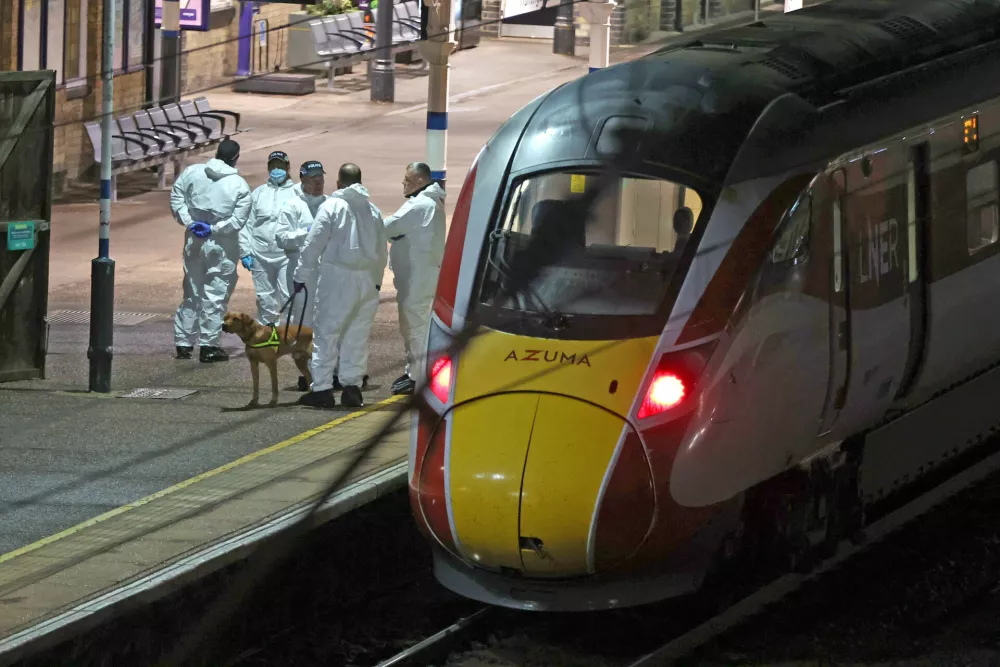 Forensic investigators on the platform by a train at Huntingdon station after a mass stabbing on a London-bound train in eastern England, in Cambridgeshire, England, Saturday, Nov. 1, 2025. (Chris Radburn/PA via AP)