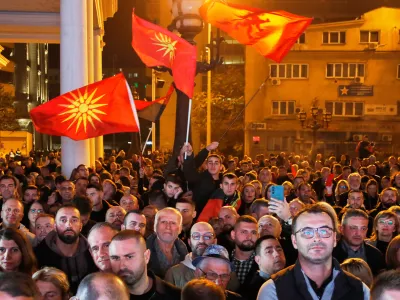 Supporters of the conservative VMRO-DPMNE party wave party flags and the old national flag as the leader Hristijan Mickoski announces a "great" victory in the local elections, at the party headquarters in Skopje, North Macedonia, on Sunday, Nov. 2, 2025. (AP Photo/Boris Grdanoski)