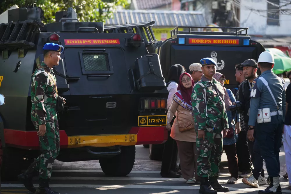 Curious onlookers look on as military personnel stand guard near a school where explosions reportedly occurred, in Jakarta, Indonesia, Friday, Nov. 7, 2025. (AP Photo/Dita Alangkara)