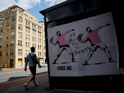 FILE PHOTO: A person walks past a banner, inspired by the work of artist Banksy, showing masked protesters throwing sandwiches, weeks after U.S. President Donald Trump ordered an increased presence of federal law enforcement to assist in crime prevention, in Washington, D.C., U.S. September 11, 2025. REUTERS/Daniel Becerril/File Photo