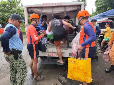 In this photo provided by the Philippine Coast Guard, rescuers evacuate people to safer grounds in Quezon province, eastern Philippines as Typhoon Fung-wong enters the country on Sunday Nov. 9 2025. (Philippine Coast Guard via AP)