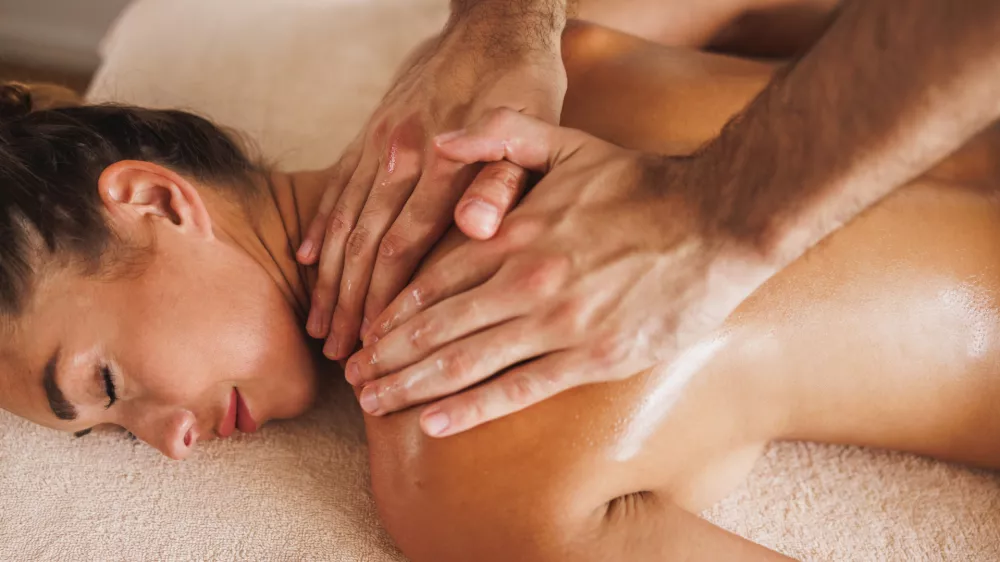 Woman enjoying during a relax massage at the cosmetology spa centre.