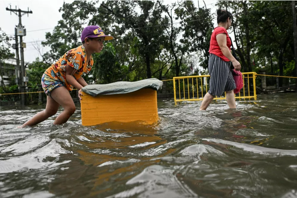 A boy pushes a styrofoam box as he wades through a flooded street after Typhoon Fung-wong hit Dagupan City, Pangasinan, Philippines, November 10, 2025. REUTERS/Noel Celisn