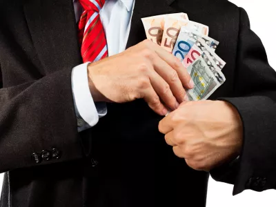 Businessman putting money (euro banknotes) in his pocket.