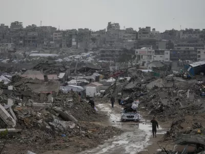 A car drives along a muddy road amid destroyed buildings in the Sheikh Radwan neighborhood of Gaza City, Friday, Nov. 14, 2025. (AP Photo/Jehad Alshrafi)