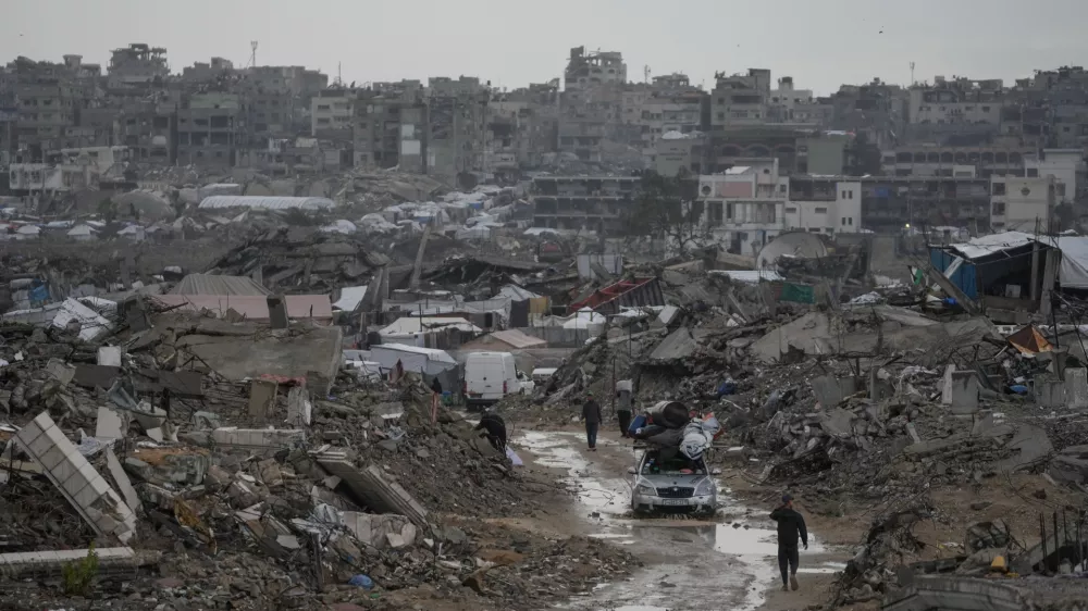 A car drives along a muddy road amid destroyed buildings in the Sheikh Radwan neighborhood of Gaza City, Friday, Nov. 14, 2025. (AP Photo/Jehad Alshrafi)