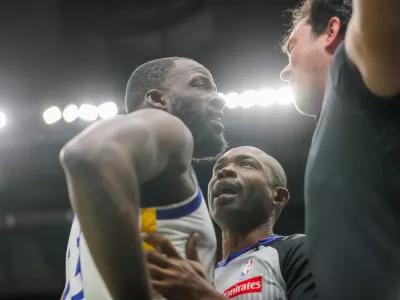 Golden State Warriors forward Draymond Green (23) is held back by referee Courtney Kirkland while talking to New Orleans Pelicans fan Sam Green during the first half of an NBA basketball game against the New Orleans Pelicans in New Orleans, Sunday, Nov. 16, 2025. (David Grunfeld/The Times-Picayune via AP)