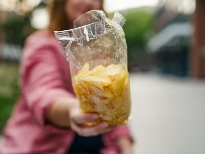 Curvy woman offering from bag of chips. Curvy woman offering from bag of potato chips. model releasedNo Use Switzerland. No Use Germany. No Use Japan. No Use Austria