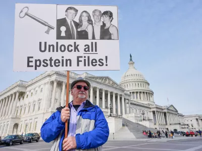 Gary Rush, College Park, MD, holds a sign before a news conference on the Epstein files in front of the Capitol, Tuesday, Nov. 18, 2025, in Washington. (AP Photo/Mariam Zuhaib)