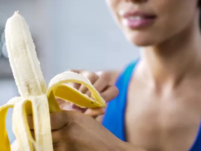 Sports woman peeling sweet banana for snack, hungry after active workout in gym, stock footage