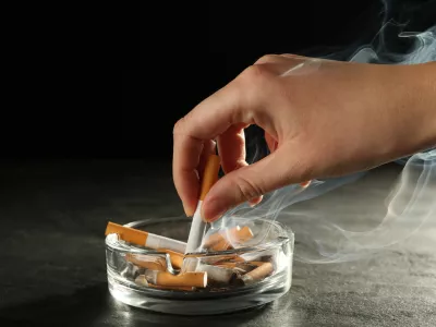 Woman extinguishing cigarette in glass ashtray