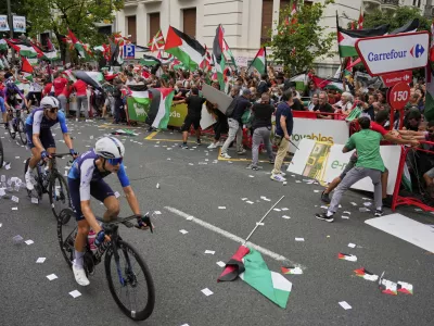 Riders of the Israel Premier Tech team compete as people holding Palestinian flags try to disrupt the eleventh stage of the Spanish Vuelta cycling race, from Bilbao to Bilbao, Spain, Wednesday, Sept. 3, 2025. (AP Photo/Miguel Oses)