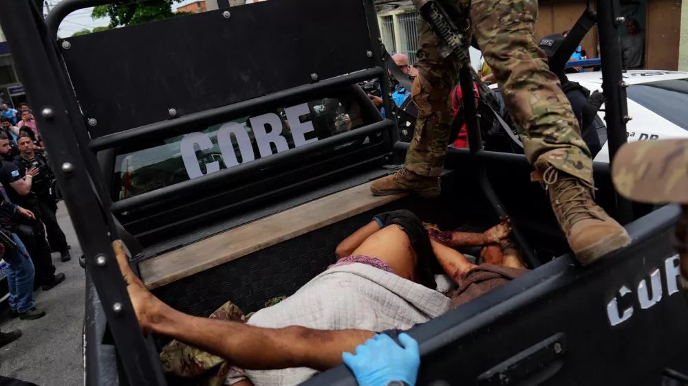EDS NOTE: GRAPHIC CONTENT - A police officer stands over bloodied people lying in the back of a police truck brought to the Getulio Vargas Hospital during a police operation against alleged drug traffickers in the Complexo do Alemao favela where the criminal organization "Comando Vermelho" operates in Rio de Janeiro, Tuesday, Oct. 28, 2025. (AP Photo/Silvia Izquierdo)