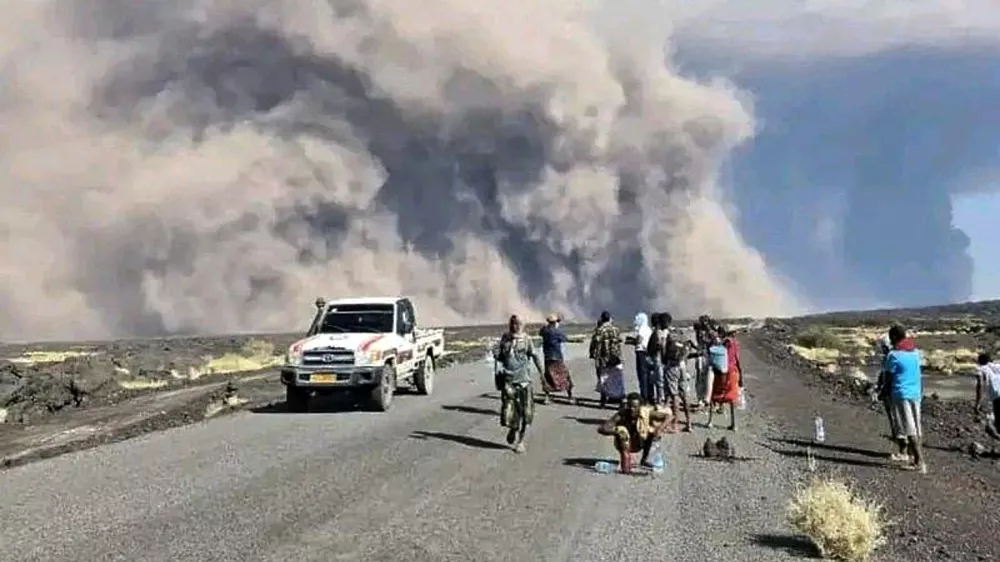 CAPTION CORRECTS HISTORY OF THE VOLCANO - In this photo released by the Afar Government Communication Bureau, people watch ash billow from an eruption of the long-dormant Hayli Gubbi Volcano in Ethiopia's Afar region, Sunday, Nov. 23, 2025. (Afar Government Communication Bureau via AP)