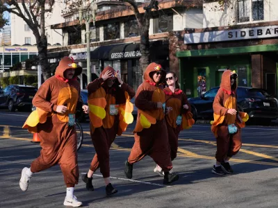 A group of people wearing turkey costumes run during the Oakland Turkey Trot in Oakland, Calif., Thursday, Nov. 27, 2025. (AP Photo/Godofredo A. V&aacute;squez)
